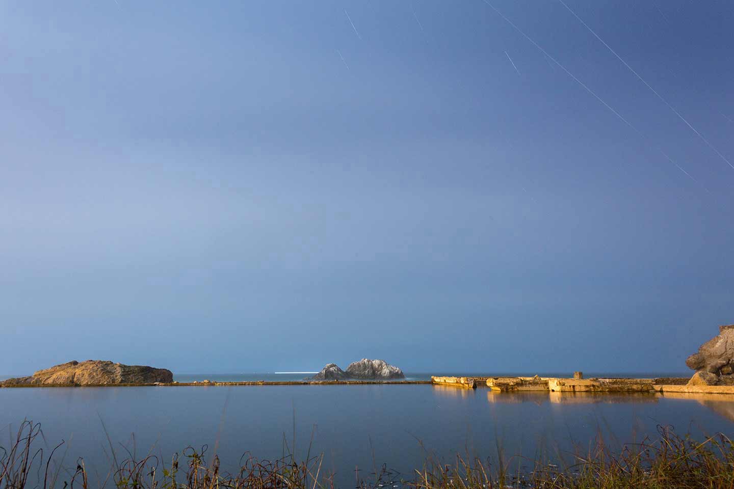 Photo of the sea and sky on the horizon with the foundations of a demolished house.