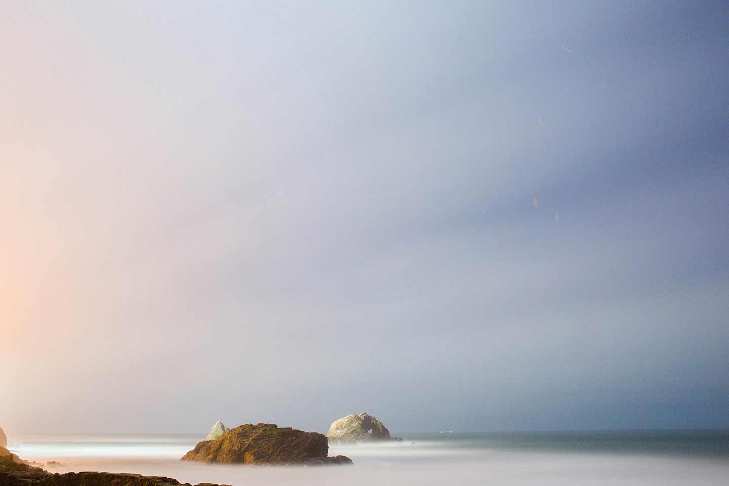 Photo of the sea with mist covering the rocky formations near the shore.